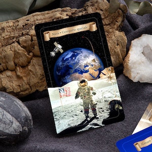 以下が含まれることがあります： 黒い背景に、上部に「Nasa - Conquete spatiale」と書かれた金色の巻物があるカード。カードには、地球を背景に月面に立っている宇宙飛行士の写真が写っている。月面に小さなアメリカ国旗が立てられている。