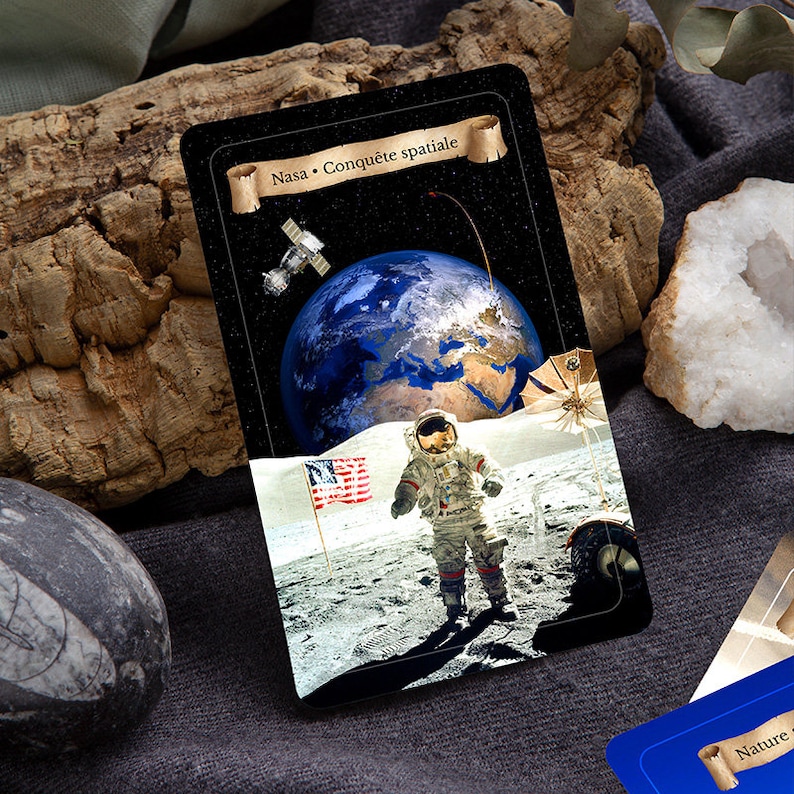 以下が含まれることがあります： 黒い背景に、上部に「Nasa - Conquete spatiale」と書かれた金色の巻物があるカード。カードには、地球を背景に月面に立っている宇宙飛行士の写真が写っている。月面に小さなアメリカ国旗が立てられている。