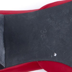 May include: Close-up of the bottom of a red shoe with a black rubber sole. The size 38 is printed on the sole.