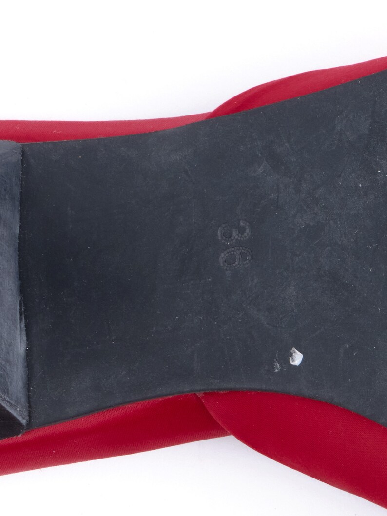 May include: Close-up of the bottom of a red shoe with a black rubber sole. The size 38 is printed on the sole.