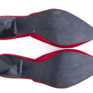 May include: A pair of red leather heeled mules with black soles. The soles are visible in the image.