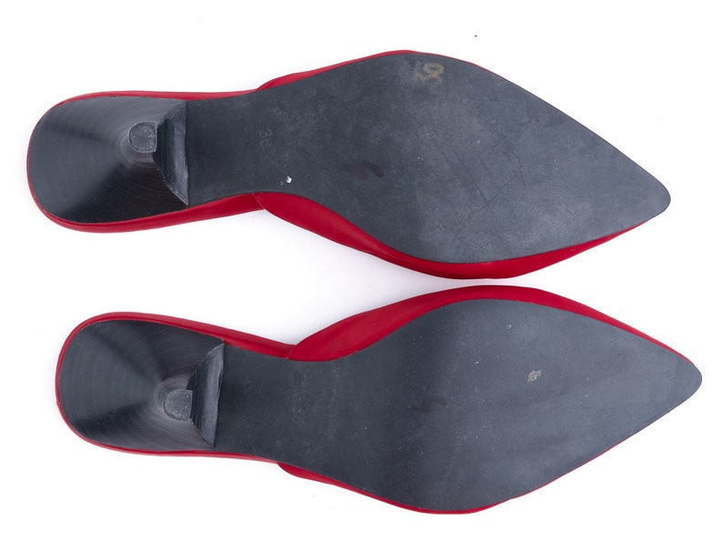 May include: A pair of red leather heeled mules with black soles. The soles are visible in the image.