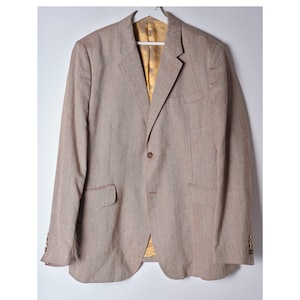 May include: A brown blazer with a single button closure and a brown and white patterned design. The blazer has a brown lining and two pockets on the front.