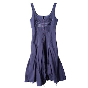 May include: A dark purple sleeveless dress with a button-down front and a flared skirt. The dress has white stitching and a raw hem, giving it a vintage look. The fabric appears to be a lightweight cotton or linen. The dress is approximately 100 cm in length.