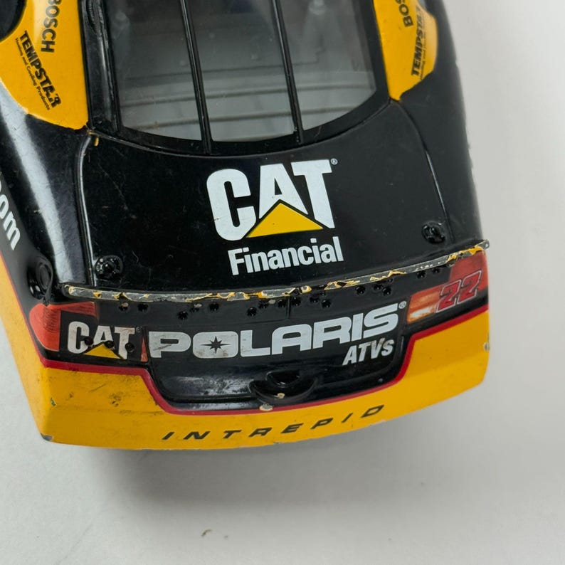May include: Close-up of a toy race car with a black and yellow design. The car features the "CAT Financial" logo and "CAT Polaris ATVs" text. The number "22" is visible on the side. The car has a sleek, aerodynamic shape.