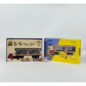 May include: A Corgi Classics Chipper truck toy set. The red and black truck has a detailed cargo bed and blue wheels. The set includes animal figurines and a box with the truck's image.