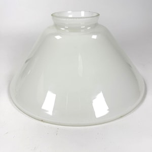 May include: A white glass lampshade with a rounded, conical form. The lampshade has a wide base that tapers to a smaller opening at the top. The glass is smooth and opaque, with a slight sheen.