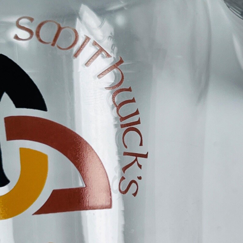 May include: Close-up of a clear glass with the name "Smithwick's" in a copper-coloured, curved font. The logo features a stylized design with black, brown, and yellow elements.