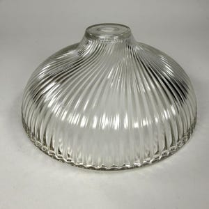 May include: A clear glass dome-shaped light fixture shade featuring a distinct swirling ribbed pattern that radiates from the centre opening towards the bottom edge. The glass is transparent with a smooth, glossy finish and a circular top aperture.