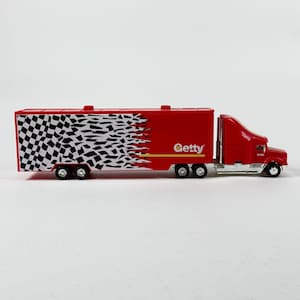 Peut inclure: Un camion semi-remorque jouet rouge avec une remorque. La remorque présente un motif de drapeau à damier noir et blanc qui s'estompe en arrière-plan rouge. Le mot "Getty" est imprimé sur le côté de la remorque en blanc.