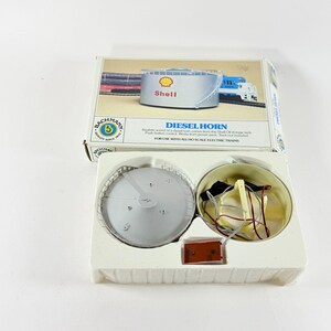 May include: A Bachmann Diesel Horn set for HO scale electric trains. The box features a Shell oil storage tank graphic. The set includes a horn component and other electrical parts. The text on the box reads "DIESEL HORN".