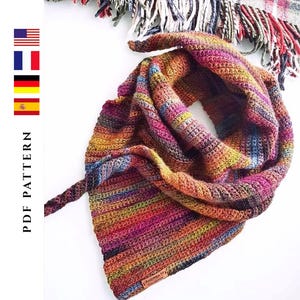 May include: A colorful, hand-crocheted scarf in a triangular shape, featuring a vibrant mix of rainbow hues. The scarf is made of soft yarn and has a textured appearance. The words "PDF PATTERN" are printed on the left side.