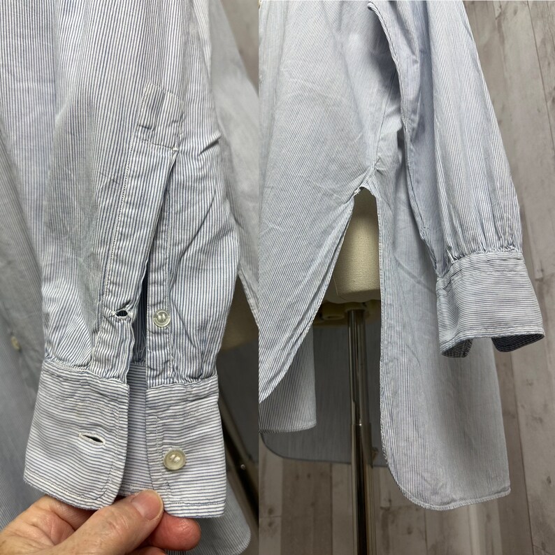 Pu&ograve; includere: Una camicia a maniche lunghe a righe blu chiaro e bianche con colletto abbottonato e polsino con un bottone. La camicia ha uno spacco laterale ed &egrave; realizzata in un tessuto leggero.