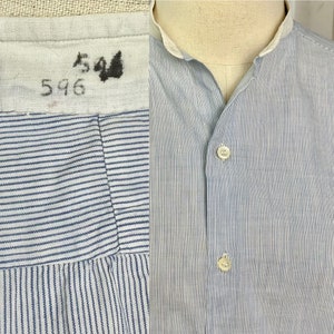 Pu&ograve; includere: Una camicia di cotone a righe blu e bianche con colletto alla coreana e chiusura con bottoni. La camicia ha un'etichetta con i numeri "544" e "596".