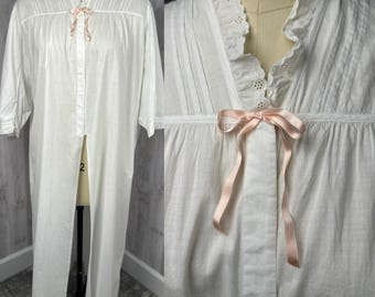 May include: White cotton nightgown with a lace trim and a pink ribbon tie. The gown has a long, flowing skirt and a fitted bodice.