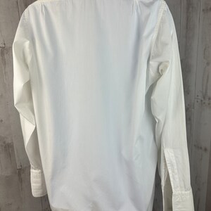 Pu&ograve; includere: Una camicia bianca a maniche lunghe con colletto alla coreana e polsini doppi.
