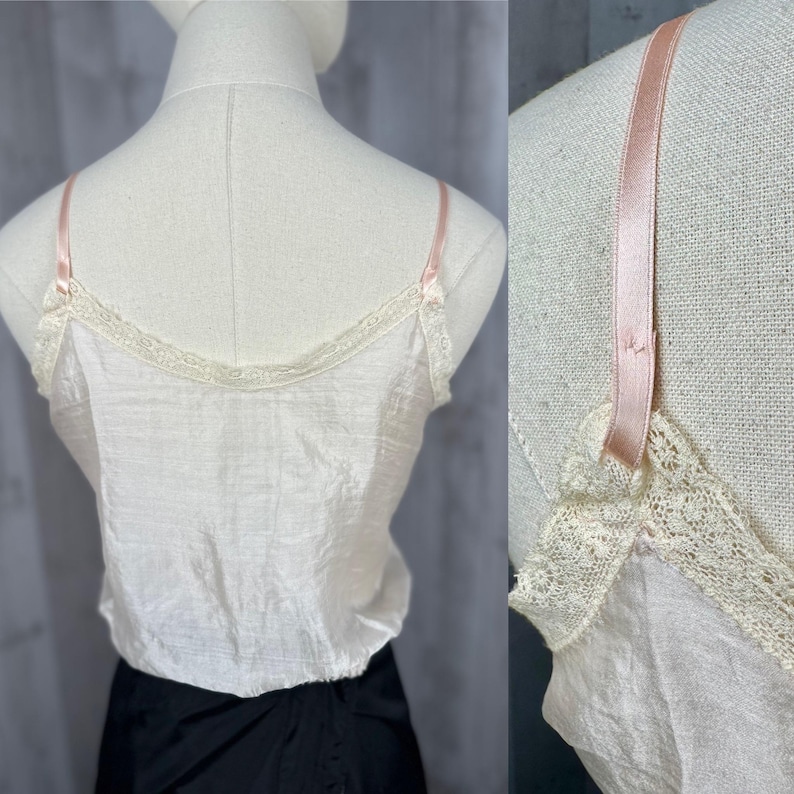 May include: A white satin camisole with delicate lace trim and thin pink straps. The camisole is worn on a white mannequin.