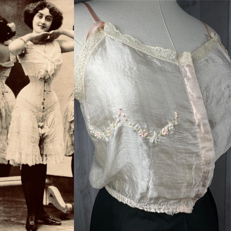 May include: A vintage, pale pink silk camisole with delicate floral embroidery and a lace trim. The camisole has a button closure at the front and a gathered elastic band at the bottom.