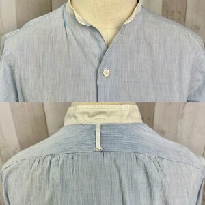 Pu&ograve; includere: Una camicia a maniche lunghe a righe blu e bianche con colletto bianco e un unico bottone di chiusura. La camicia ha un colletto alla coreana e una vestibilit&agrave; rilassata.