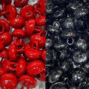 May include: A close-up image of two groups of buttons. One group is red and the other is black. Both groups are shiny and have a small loop on top.