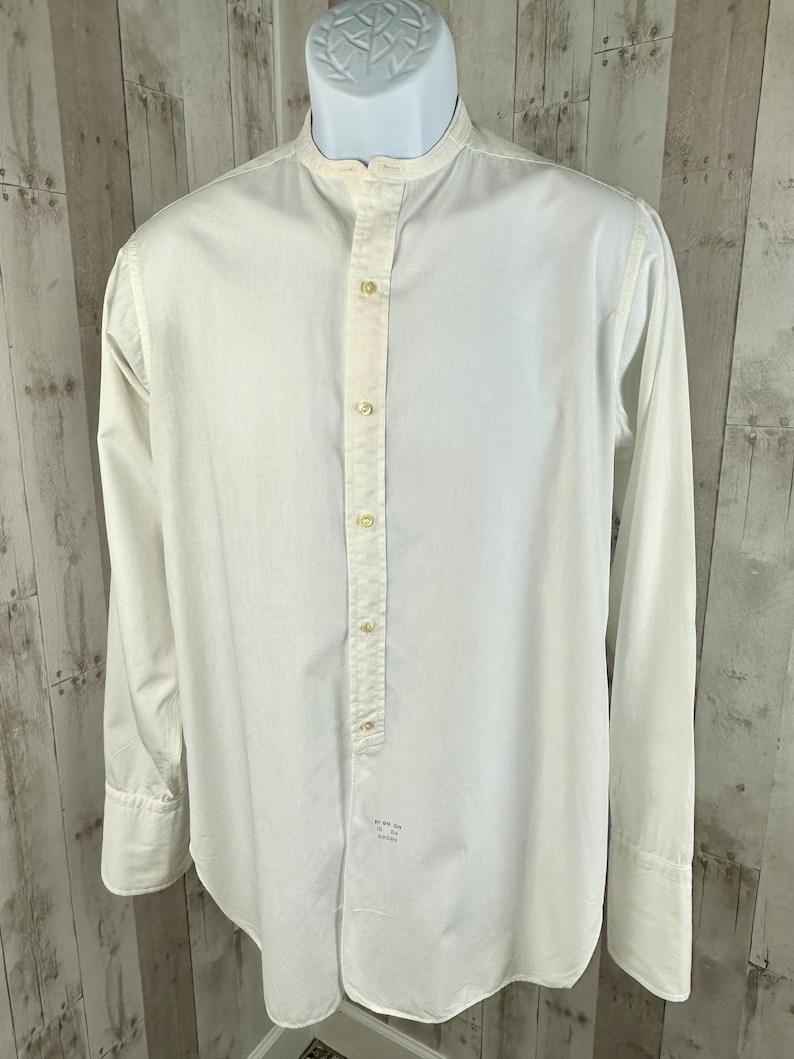 Pu&ograve; includere: Una camicia bianca a maniche lunghe con bottoni, colletto alla coreana e una singola patta con bottoni. La camicia ha una vestibilit&agrave; rilassata ed &egrave; realizzata in un tessuto leggero.