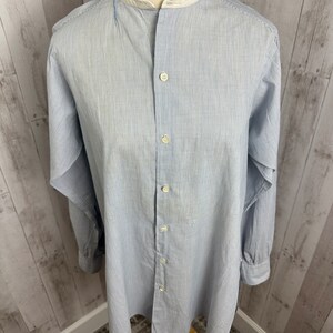 Pu&ograve; includere: Una camicia a maniche lunghe a righe blu chiaro con colletto alla coreana bianco e chiusura con bottoni.