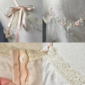 May include: A vintage white slip dress with delicate lace trim and a pink satin ribbon bow. The dress features embroidered floral details and a button closure.