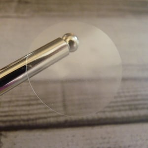 May include: A clear, round sticker with a silver applicator.