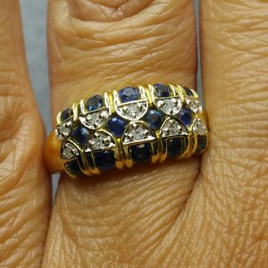 May include: A gold ring with a band of alternating blue sapphires and diamonds. The ring is set in a gold band and has a polished finish.