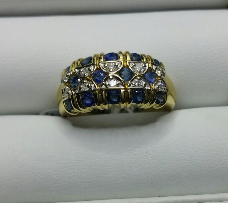 May include: A gold band ring with a design of alternating blue sapphires and white diamonds.