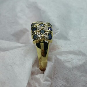 May include: A gold ring with a rectangular setting featuring alternating blue sapphires and white diamonds.