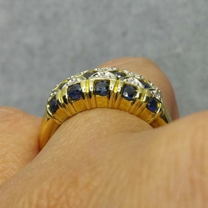 May include: A gold band ring with a row of blue sapphires and small diamonds set in the band.