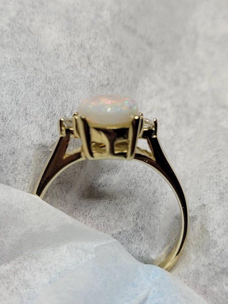 May include: A gold ring with a white opal gemstone and two smaller diamonds on the band.