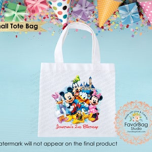 Puede incluir: Bolsa de tela blanca con una imagen colorida de Mickey Mouse y sus amigos frente al Castillo de Cenicienta. El texto "JONATHAN'S 2ND BIRTHDAY" est&aacute; impreso en la bolsa.