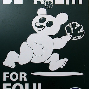 May include: A green sign with white text that reads "BE ALERT FOR FOUL BALLS!"  A cartoon white bear wearing a baseball glove is catching a ball. The Chicago Cubs logo is in the bottom right corner.