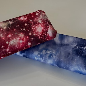 May include: Two pieces of fabric with a galaxy print. One is red with white stars and the other is blue with white stars.