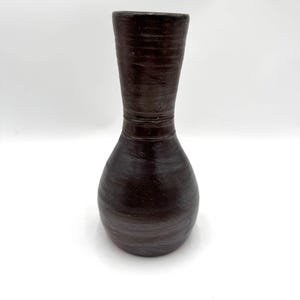 May include: A dark brown ceramic vase with a rounded bottom and a narrow neck. The vase has a textured, slightly glossy finish.