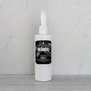 May include: A white spray bottle with a black label that says "KÖNIG Black Cherry  Blacksmith  Gun Oil & Lubricant  Precision Made Spray  Frederick, MD"