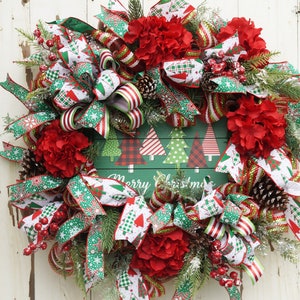 May include: A Christmas wreath with red and green plaid ribbon, red flowers, pine cones, and a green sign that says "Merry Christmas".