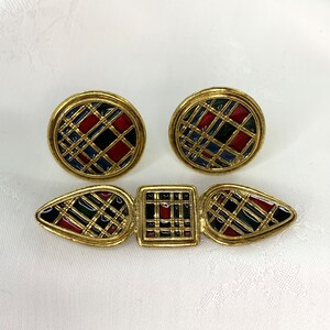 May include: A vintage jewelry set featuring gold-toned metal earrings and a brooch. The earrings are oval-shaped, and the brooch has a geometric design. Each piece has a colorful plaid pattern in red, blue, black, and green.