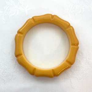 May include: A yellow plastic bangle bracelet with a ridged design.