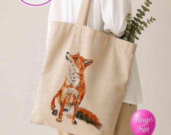 Puede incluir: Un bolso de tela beige con una ilustración detallada de un zorro sentado mirando hacia arriba. El bolso tiene dos correas para el hombro e incluye un gráfico circular con el texto Personalise Me y un globo rosa con el texto Heaps of Fun.