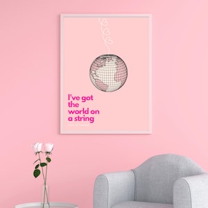 May include: A pink and white printable wall art print with a globe on a string of hearts. The text reads "I've got the world on a string".