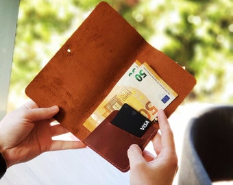 May include: A brown leather wallet with a credit card and a 50 euro bill inside. The wallet is open and the inside is visible.