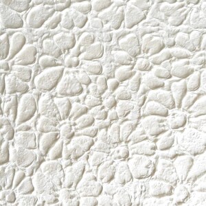 May include: White textured wall with a pattern of raised, rounded shapes resembling stones.