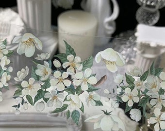 Puede incluir: Una hoja de papel adhesivo transparente con un diseño floral blanco. El diseño presenta delicadas flores blancas con hojas verdes, dispuestas en una fila horizontal.