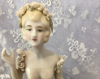 Antique reproduction half doll "Adrienne " painted in cream with flowers in her hair and at shoulders