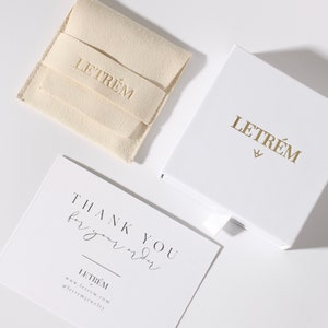 May include: A white box and card with gold lettering and a beige pouch. The box and pouch have the brand name "LETR&Eacute;M" printed on them. The card reads "THANK YOU for your order" with the brand's website and social media handle.