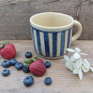 Handmade white ceramic mug with blue vertical stripe decor
