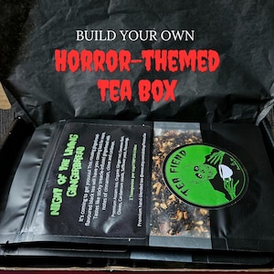 May include: A black box with the words "BUILD YOUR OWN HORROR-THEMED TEA BOX" in red. Inside, a tea bag labelled "NIGHT OF THE LIVING GINGERBREAD" and a clear bag with tea and a "TEA FIEND" sticker featuring a skeleton.
